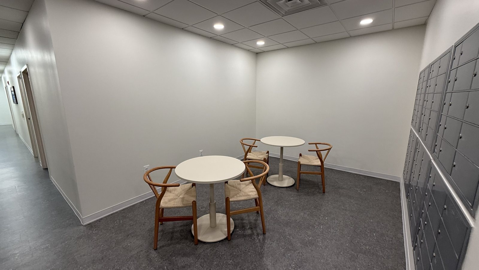 Café tables with oak wishbone chairs beside the private tenant mailboxes
