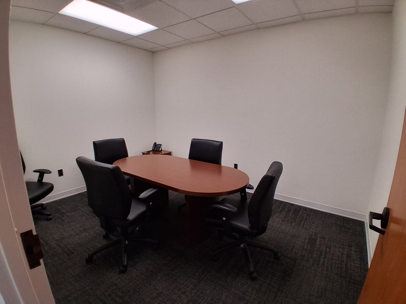 A small conference room with an oval table and four chairs