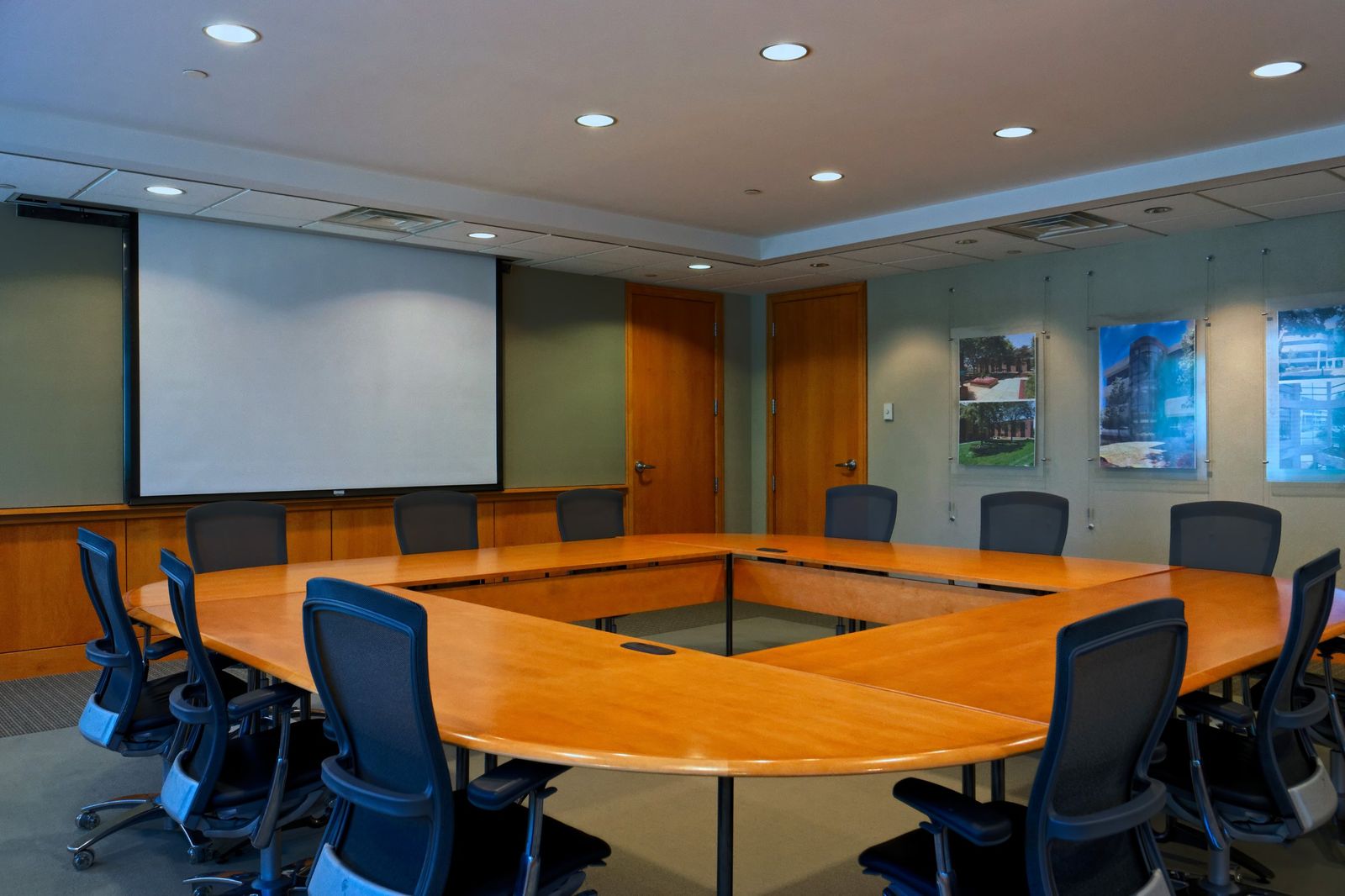 Conference center with a large U-shaped wood table and projection screen