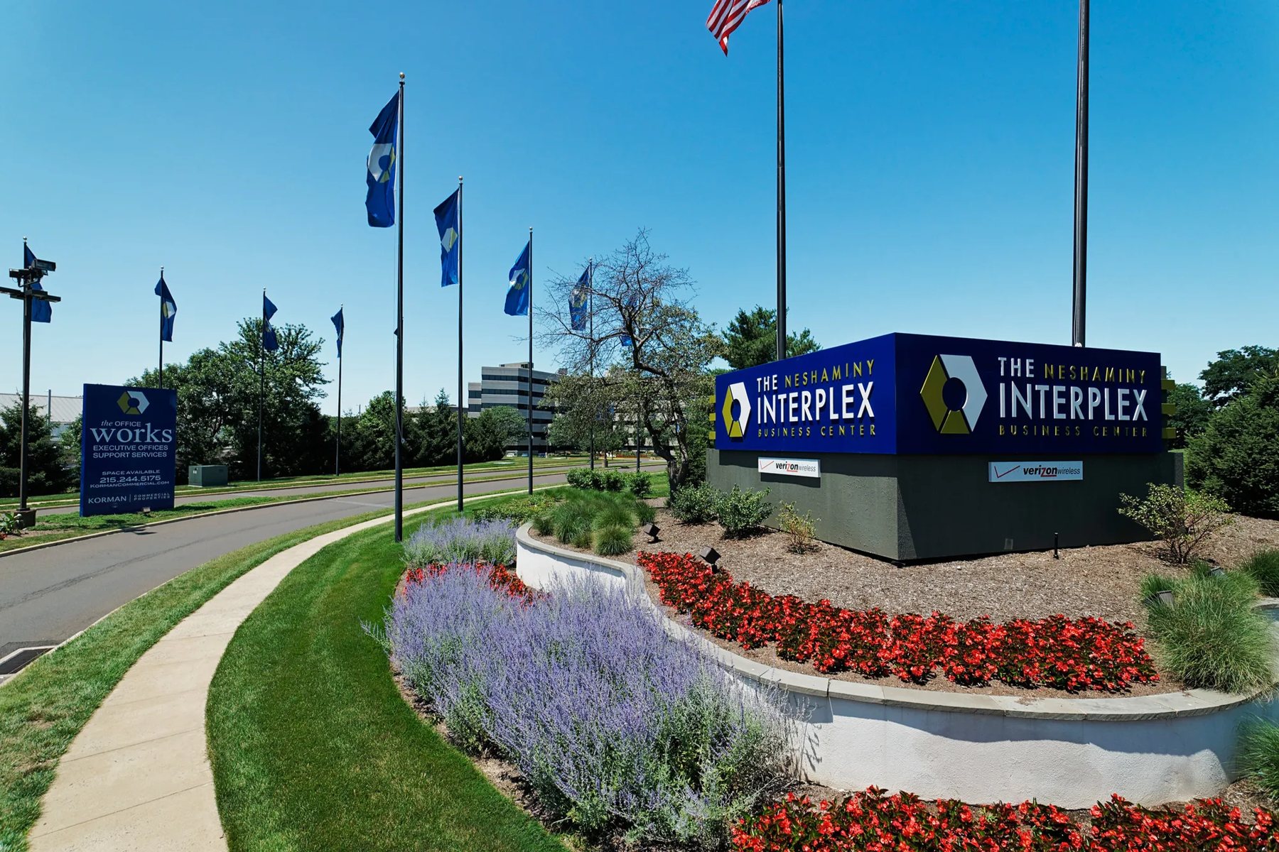 The Interplex entrance sign with flags and flower beds