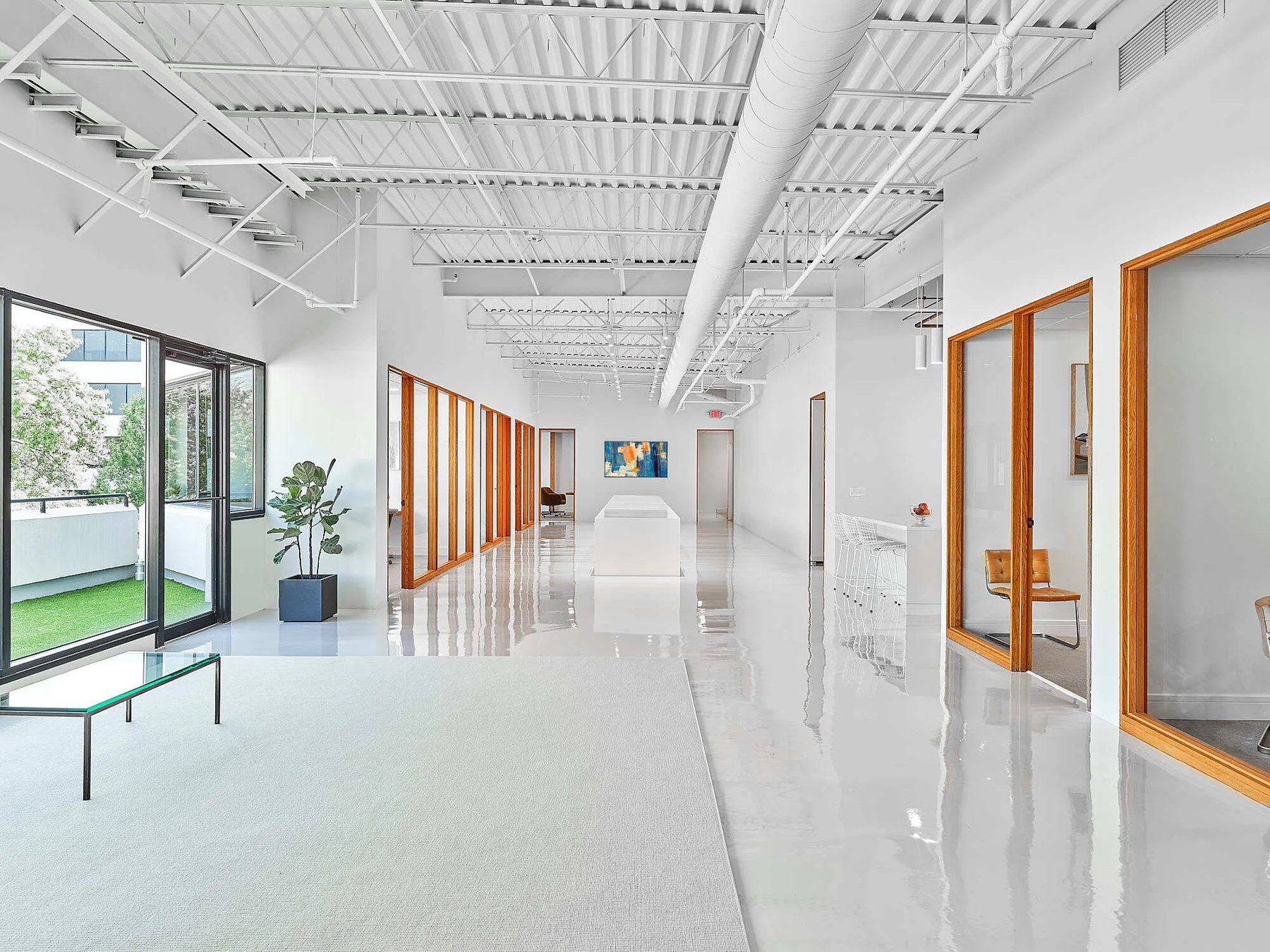 A renovated office suite with white floors, oak-framed glass offices and an outdoor terrace